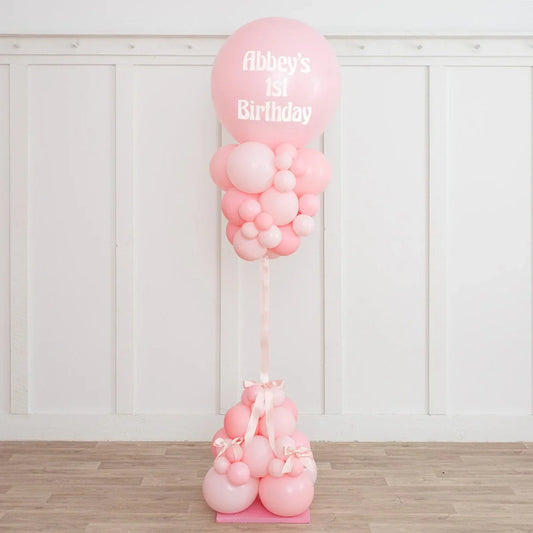 Pink balloon pillar decorated with smaller pink balloons and ribbons, celebrating Abbey's 1st birthday