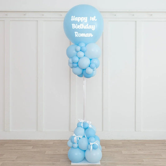 Blue balloon pillar decoration with Happy 1st Birthday Roman text for kid's party