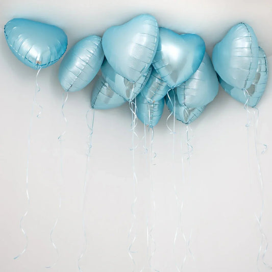 Cluster of baby blue heart-shaped foil helium balloons floating near a white ceiling with curled ribbons
