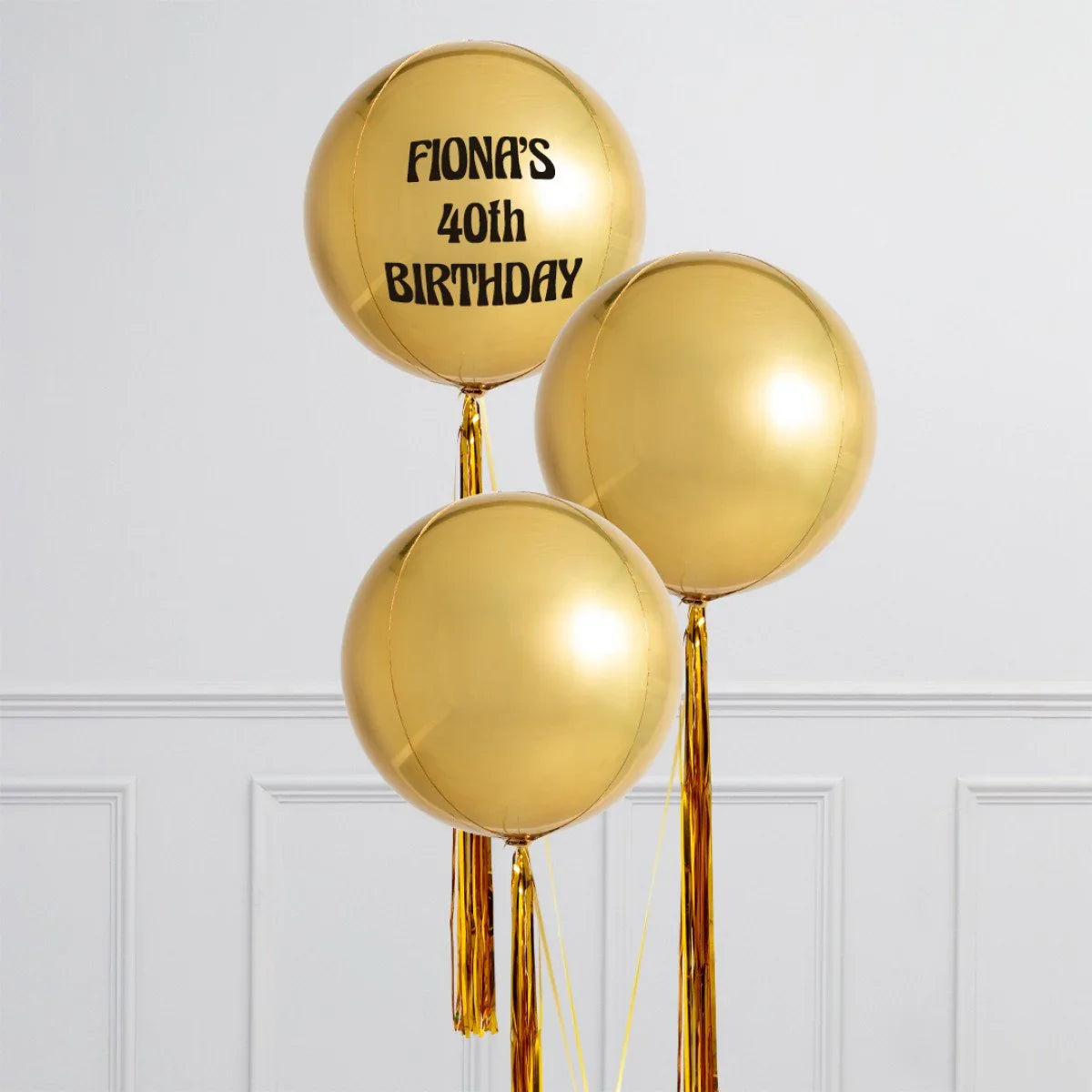 Three gold orb balloons with tassels, one personalized with 'Fiona's 40th Birthday' text