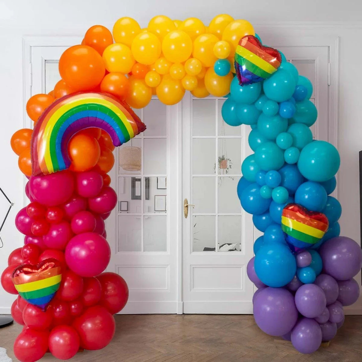 Colorful rainbow arch balloon decoration with red, orange, yellow, blue, and purple balloons indoors