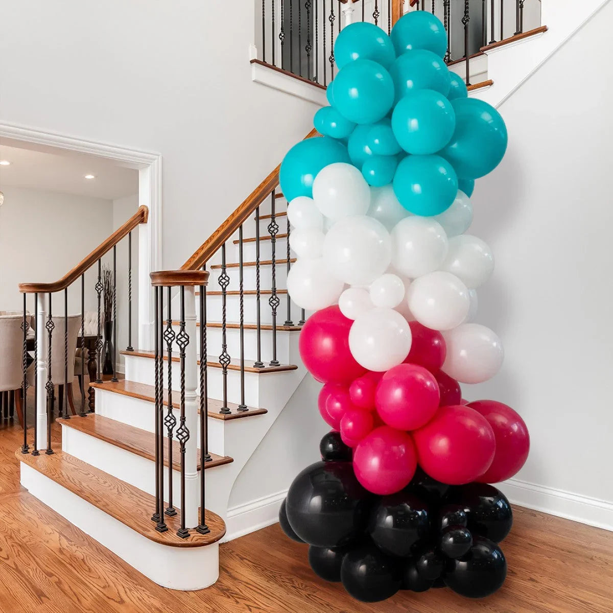 Colorful balloon pillar decoration in blue, white, red, and black by wooden staircase indoors