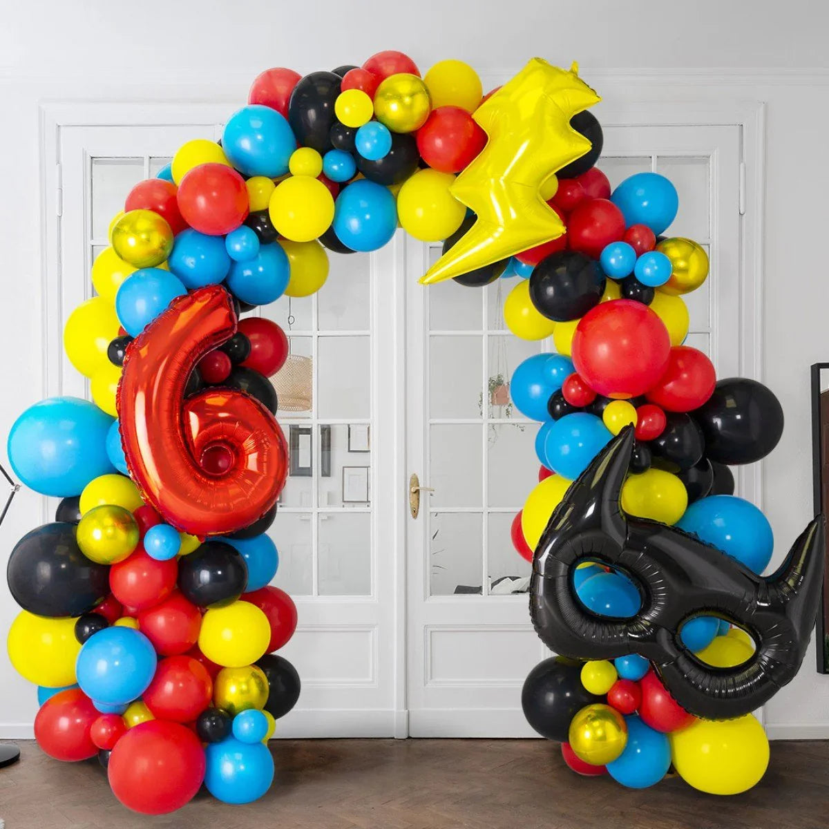 Colorful balloon arch with red number 6, yellow lightning bolt, and black superhero mask balloons