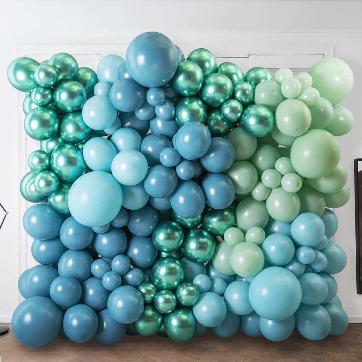 Blue and green balloon wall decoration with various sizes in a room for event backdrop