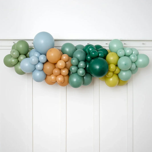 Colorful balloon garland in pastel green, blue, brown, and yellow shades decorating white wall