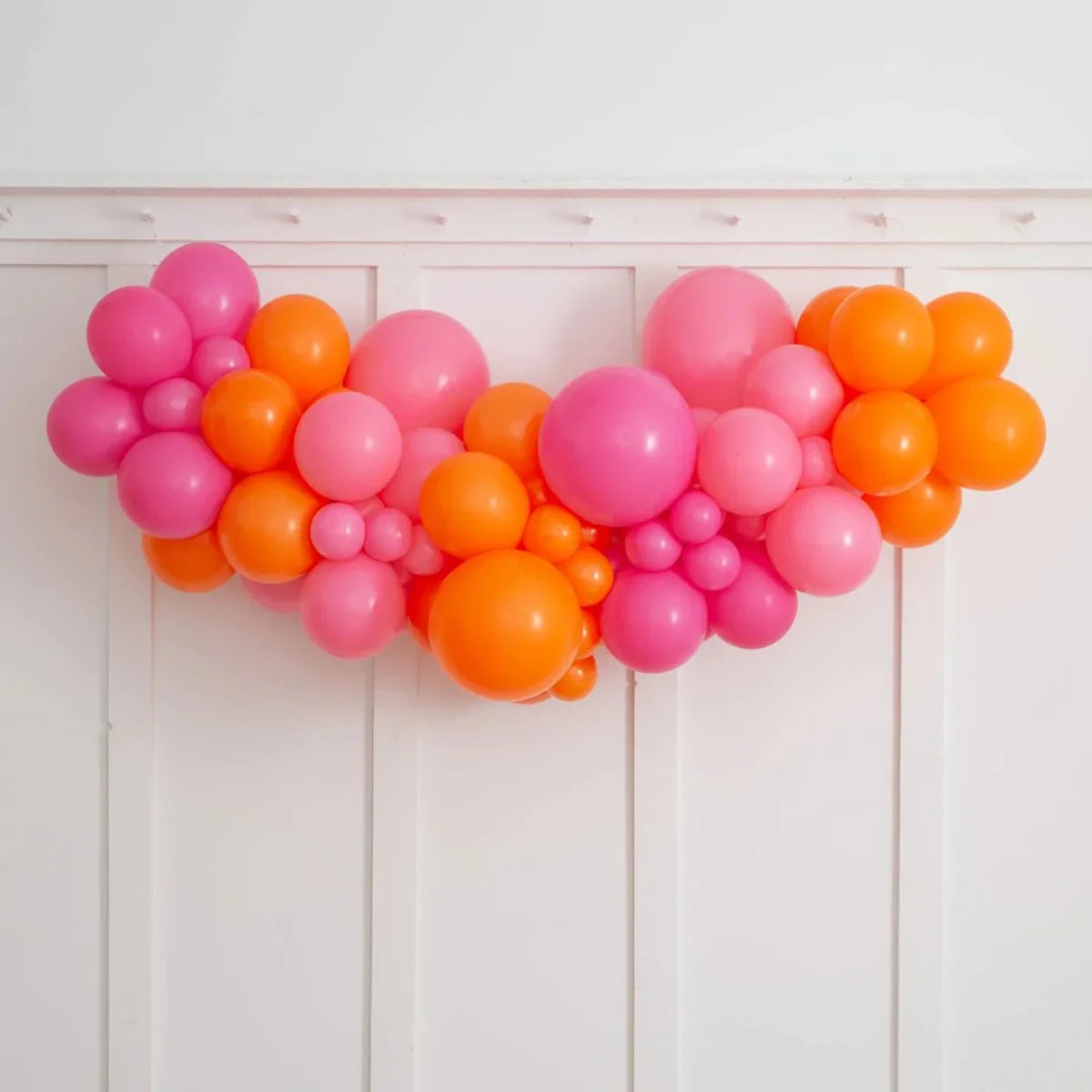 Flamingo pink and bright orange inflated balloon garland on white wall backdrop