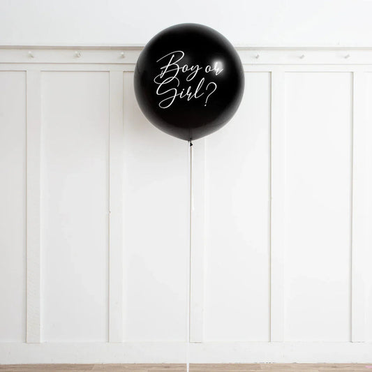 Large black gender reveal balloon with white "Boy or Girl?" text against white paneled wall