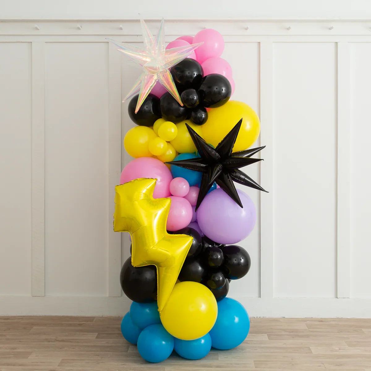 Colorful balloon pillar with black, yellow, pink, blue, purple balloons and star-shaped decorations indoors