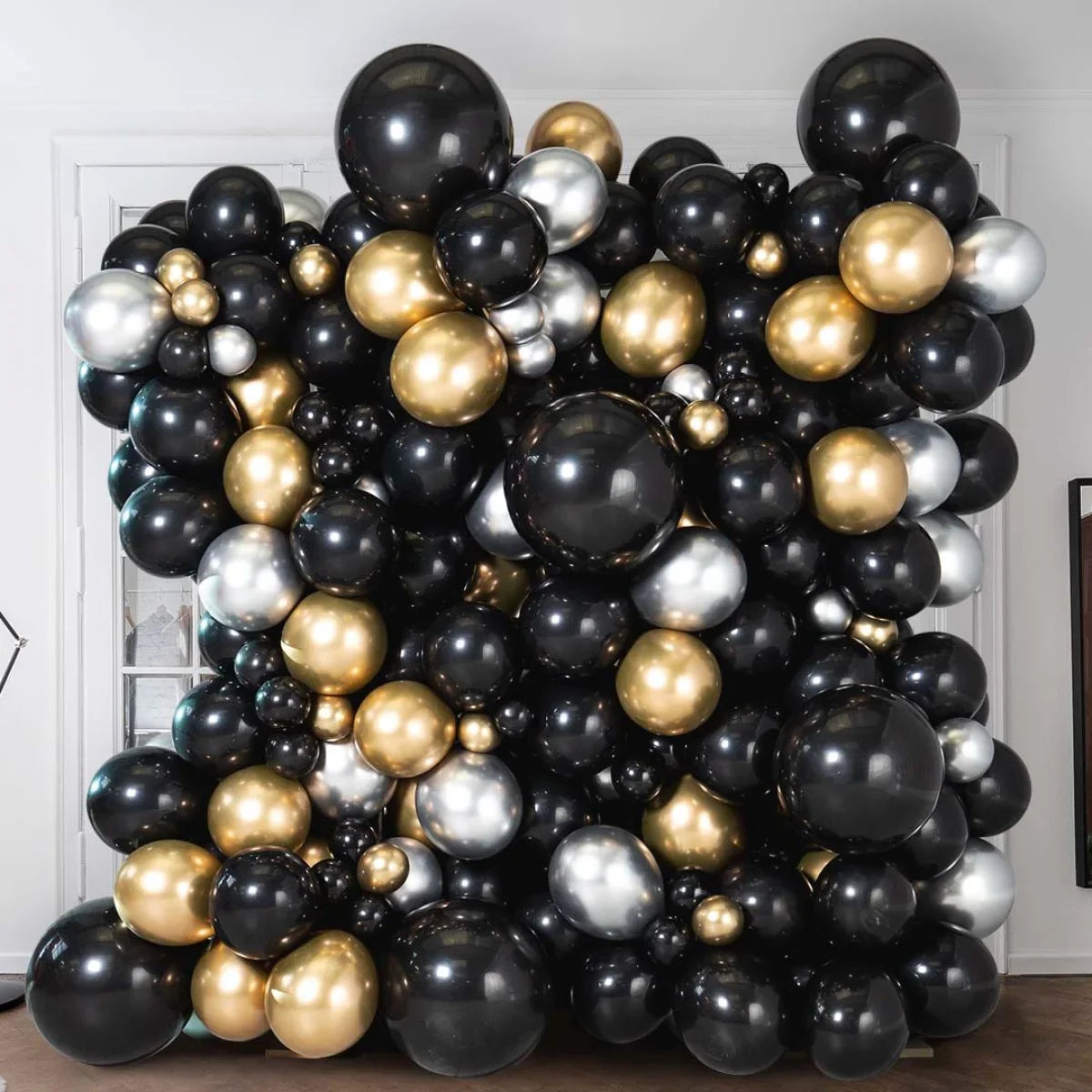 Black, gold, and silver balloon wall decoration in elegant indoor setting