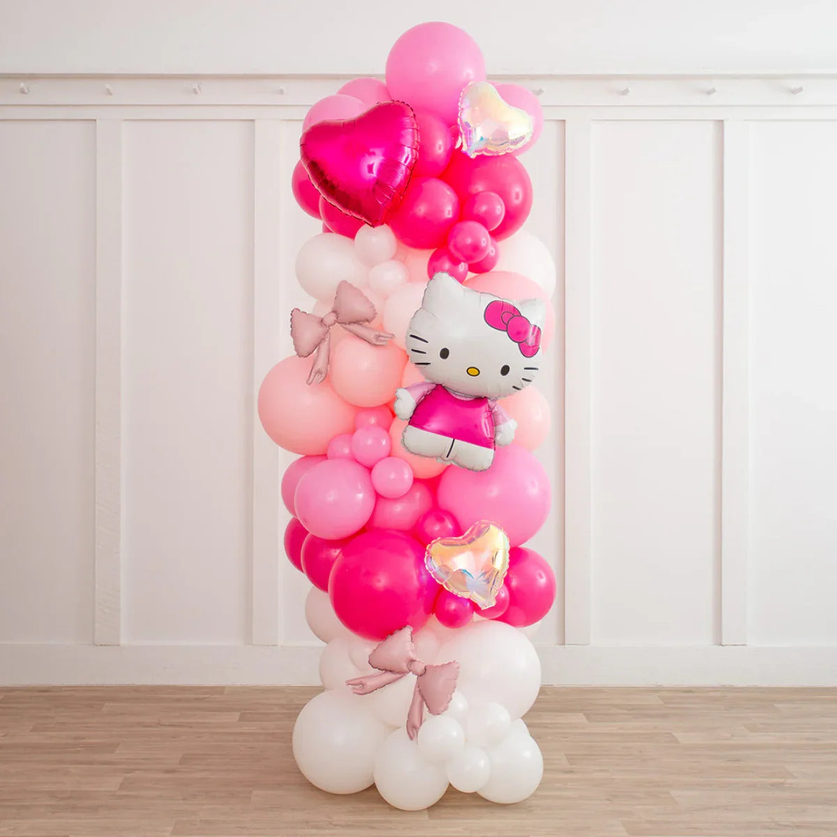 Hello Kitty balloon pillar with pink, white, and heart-shaped balloons indoors on wooden floor