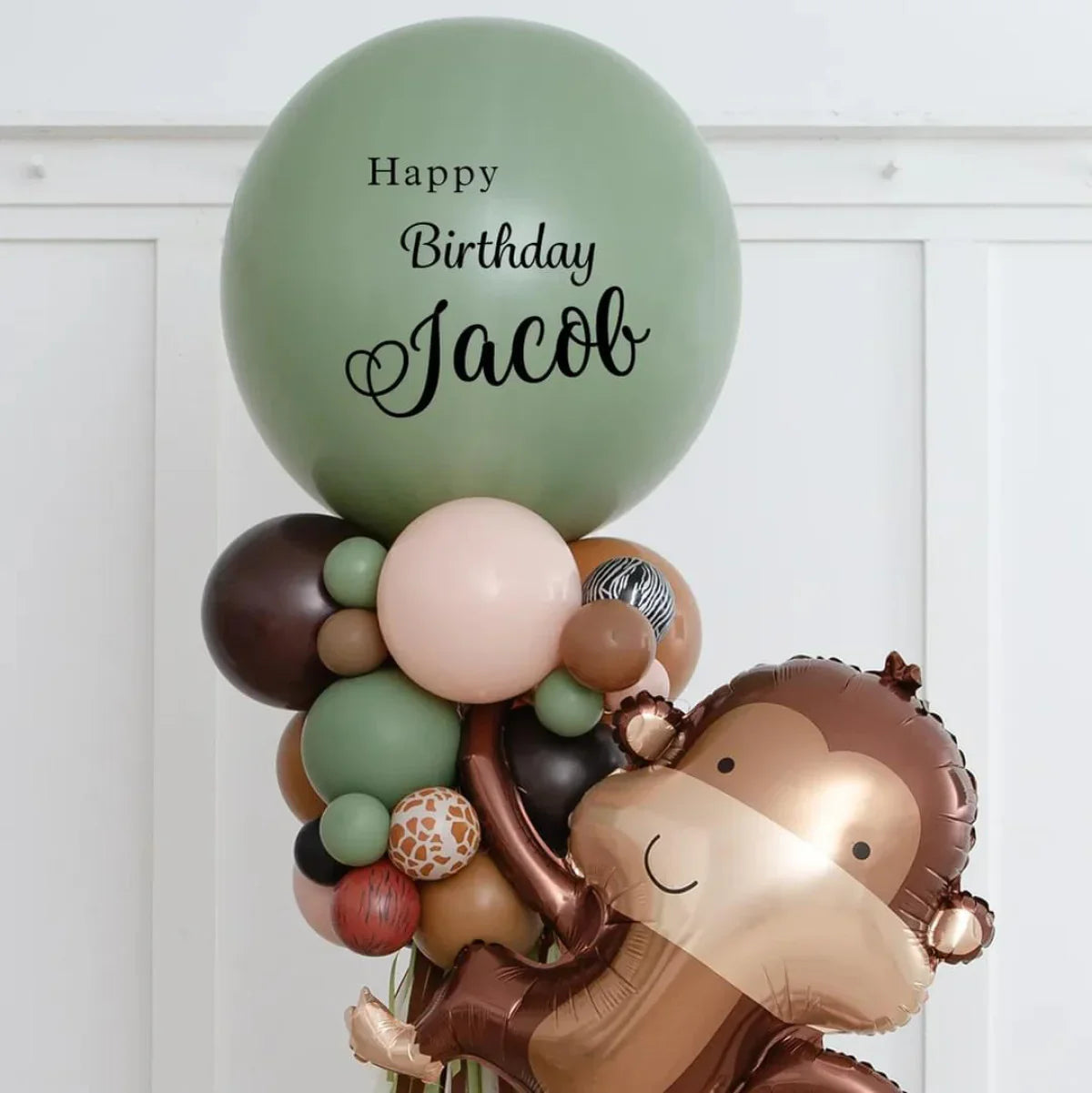 Jungle-themed birthday balloon arrangement with personalized green balloon and monkey foil balloon