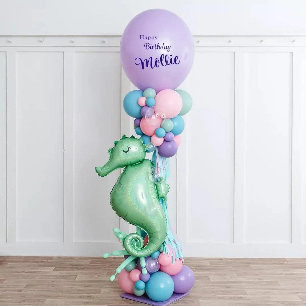 Tall pastel balloon pillar with green seahorse foil balloon and happy birthday Mollie message