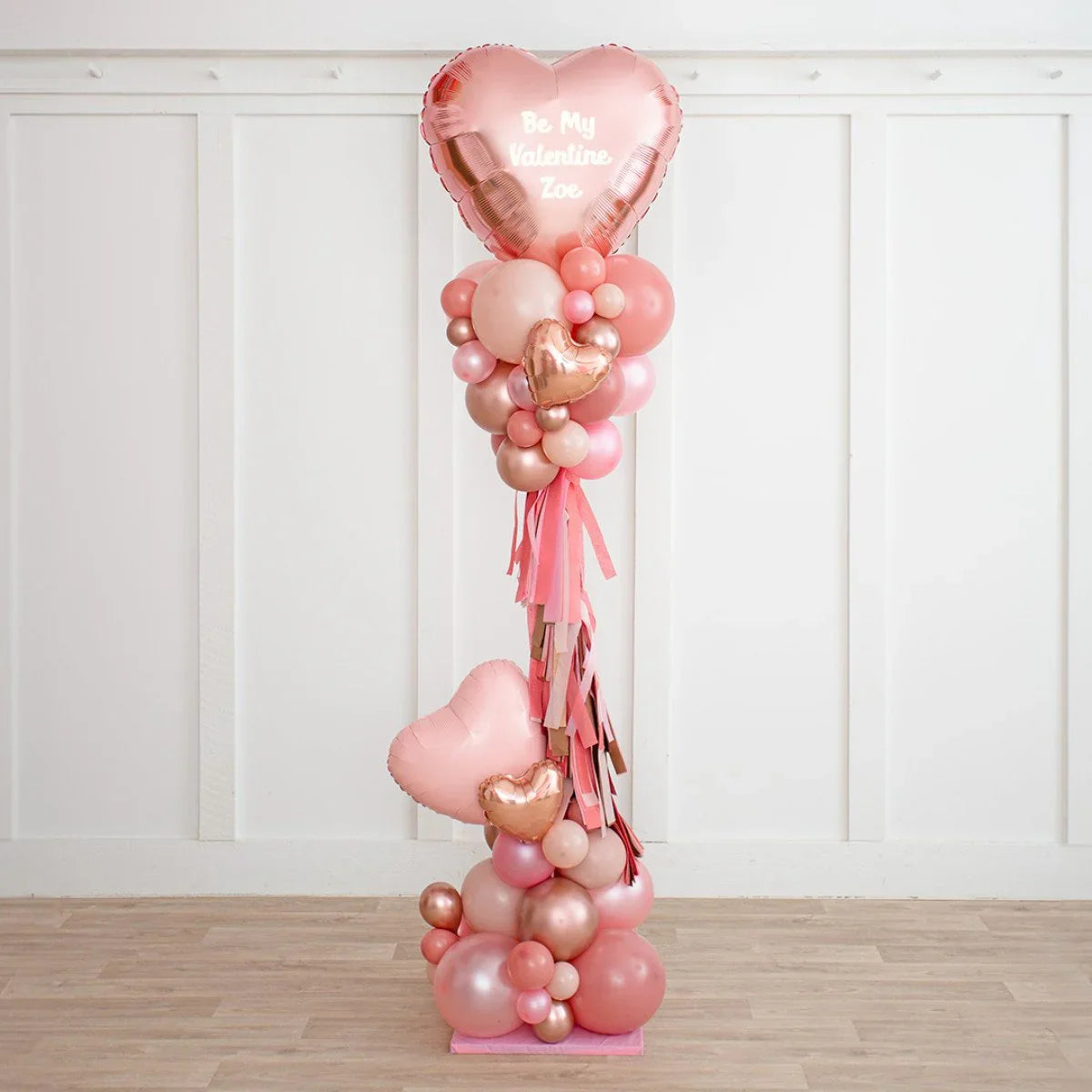 Pink and rose gold heart balloon pillar with personalized Valentine message in white room