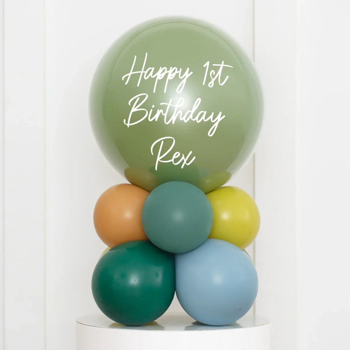 Personalized green birthday bubble balloon with text Happy 1st Birthday Rex, surrounded by smaller colorful balloons