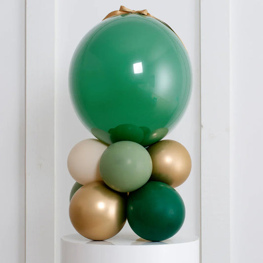 Forest green and gold air-filled balloon stack decoration on white pedestal