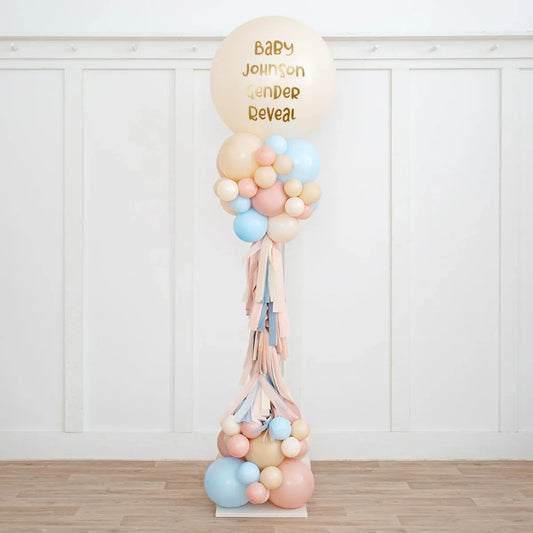 Personalized neutral pink and blue balloon pillar for baby gender reveal party in a white room