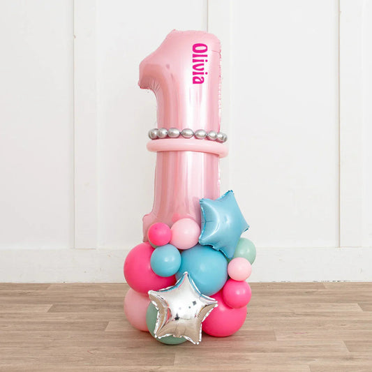 Pink number 1 balloon with name Olivia and colorful balloon cluster on wooden floor