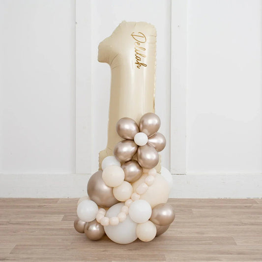 Cream number 1 balloon stack with personalized gold text and pearl balloons arranged in flower shape
