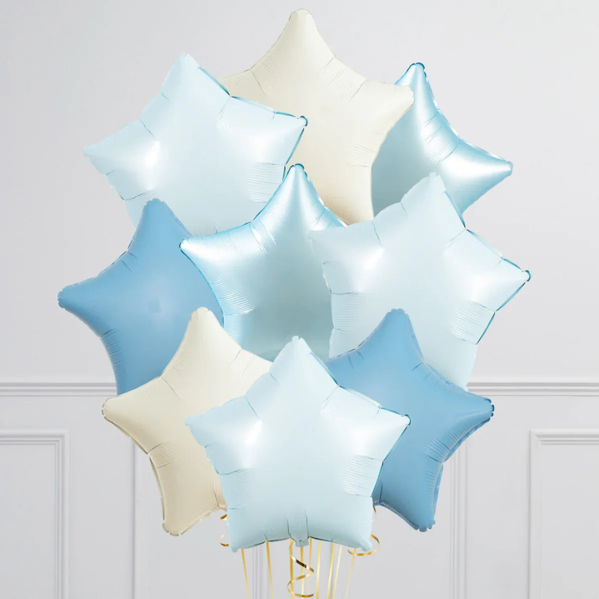 Cluster of light blue and cream star-shaped inflated foil balloons against white wall