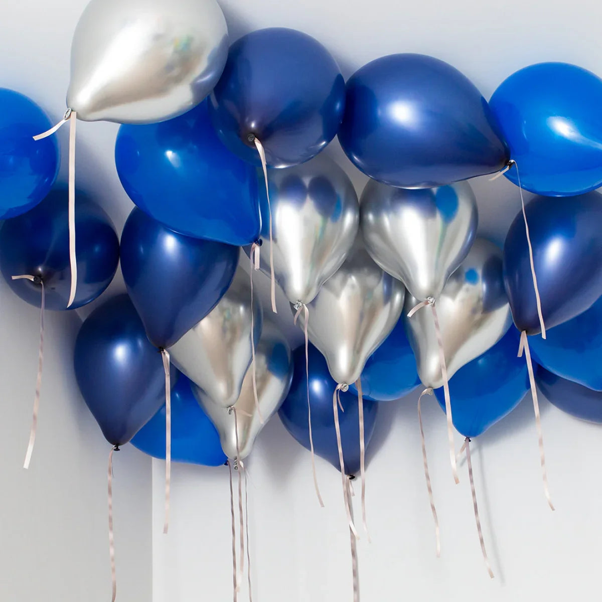 Cluster of blue and silver helium balloons floating near a white ceiling for party decoration