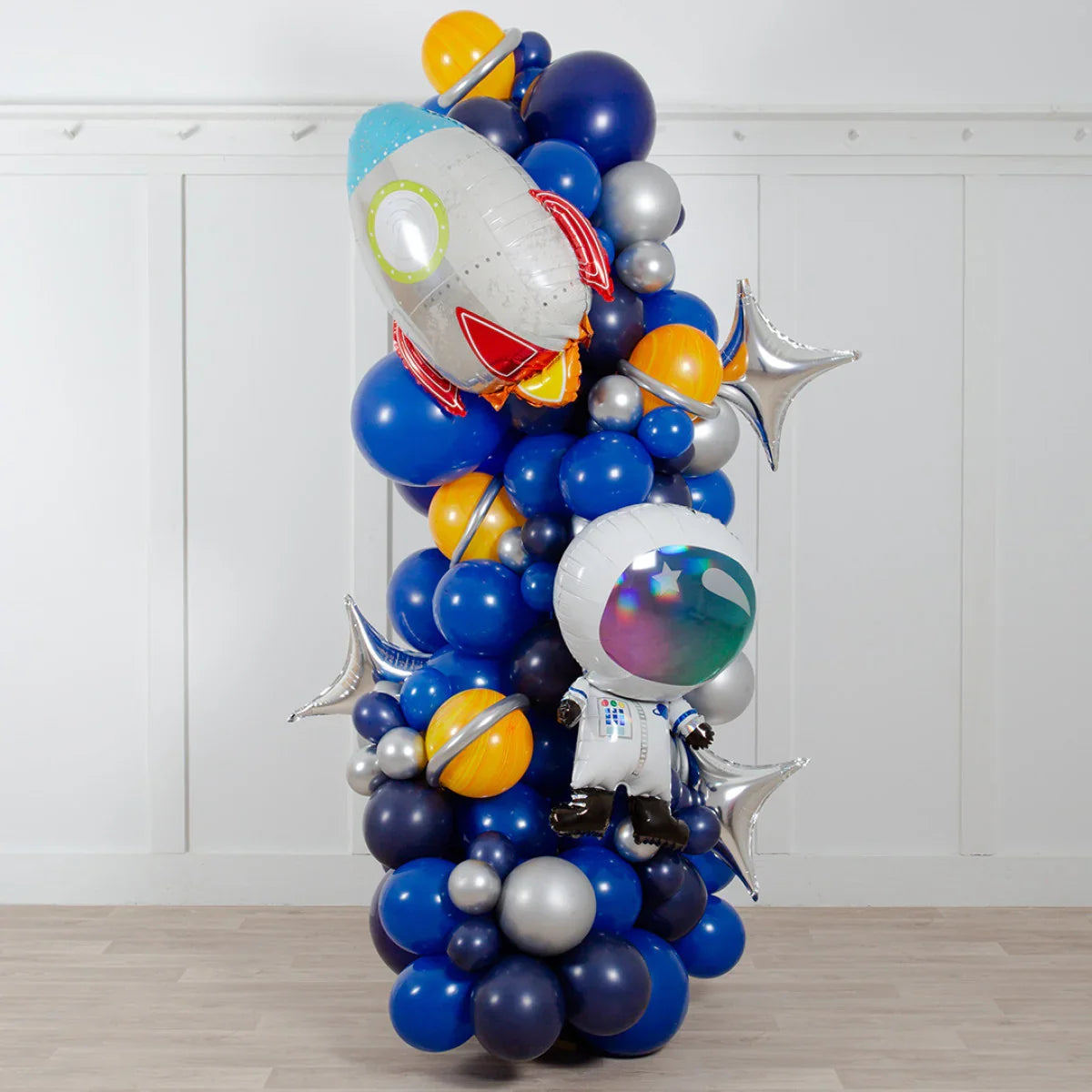 Space-themed balloon pillar with rocket, astronaut, planets, and star-shaped foil balloons