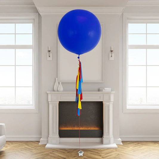 Large blue helium balloon with colorful tassels floating in elegant living room above fireplace