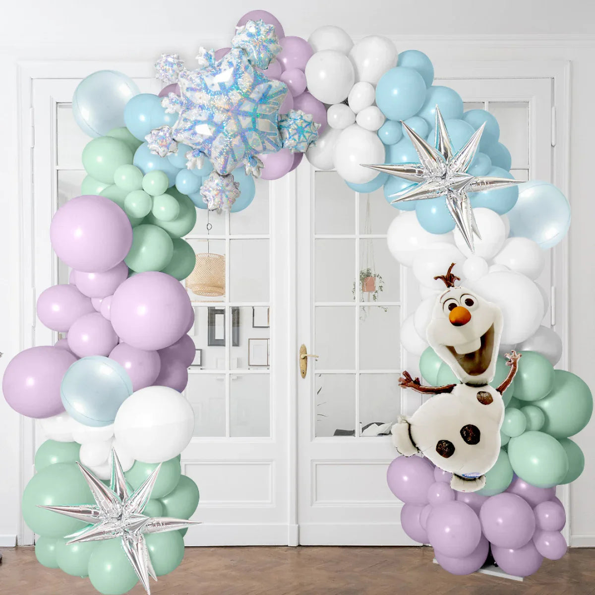 Frozen-themed balloon arch with pastel balloons, silver stars, and Olaf character indoors