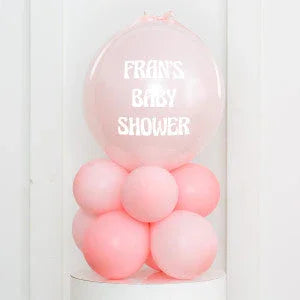 Pink balloon decoration with large clear balloon reading 'Fran's Baby Shower' at event