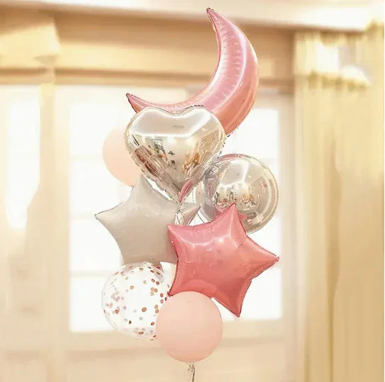 Cluster of pink, silver, and confetti balloons shaped like a crescent moon, stars, and hearts indoors
