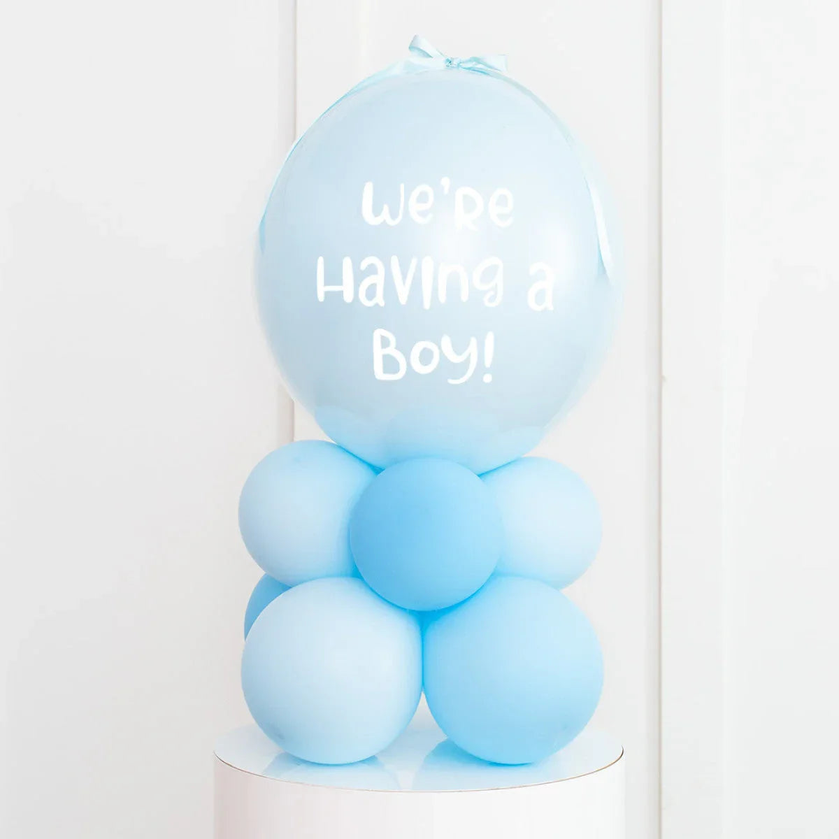 Personalised baby blue balloon stack with We’re Having a Boy text for gender reveal