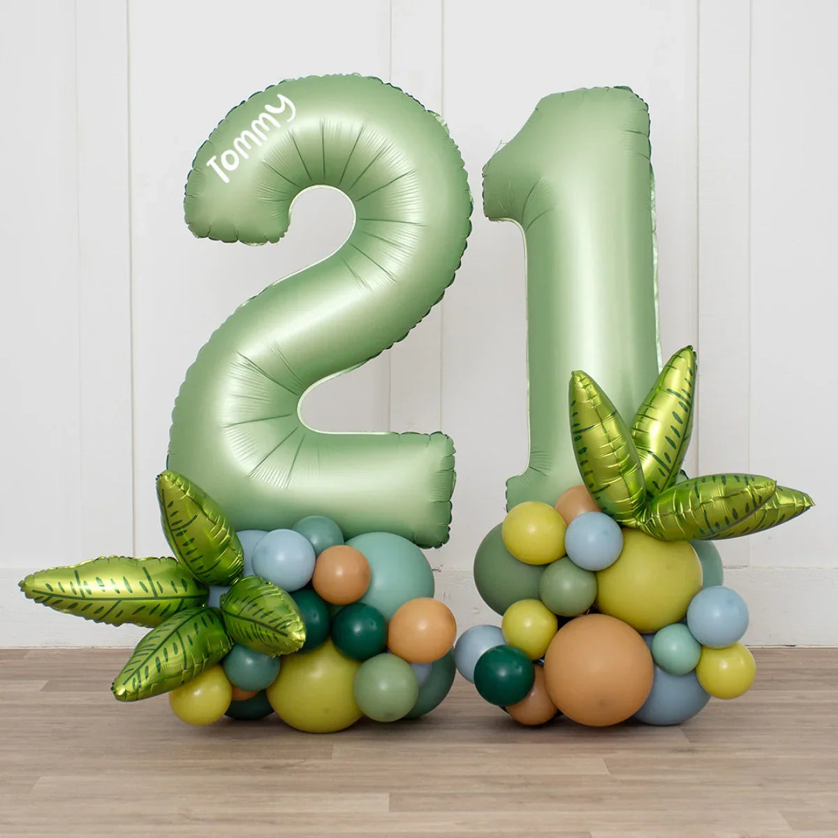 Large green foil balloons shaped as number 21 with colorful balloons and green leaf foil accents on floor