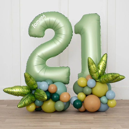 Large green foil balloons shaped as number 21 with colorful balloons and green leaf foil accents on floor