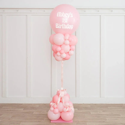 Pink balloon pillar decorated with smaller pink balloons and ribbons, celebrating Abbey's 1st birthday