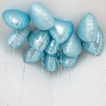 Cluster of baby blue heart-shaped foil helium balloons floating near white ceiling