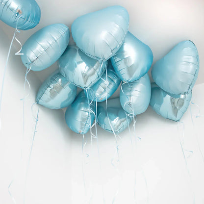 Cluster of baby blue heart-shaped foil helium balloons floating against white ceiling