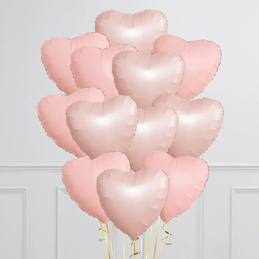 Bunch of baby pink and blush heart-shaped foil balloons with gold ribbons indoors