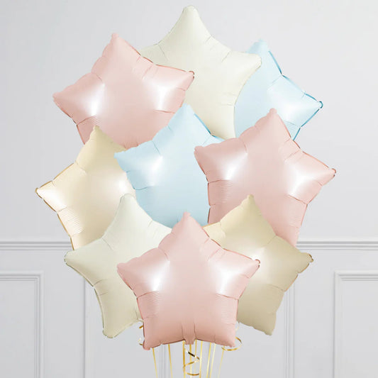 Cluster of pastel star-shaped foil balloons in pink, blue, and cream against white wall
