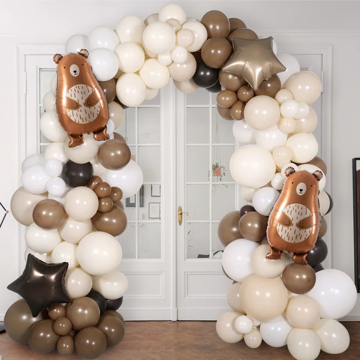 Neutral beige and brown balloon arch with two bear-shaped and star-shaped balloons indoors