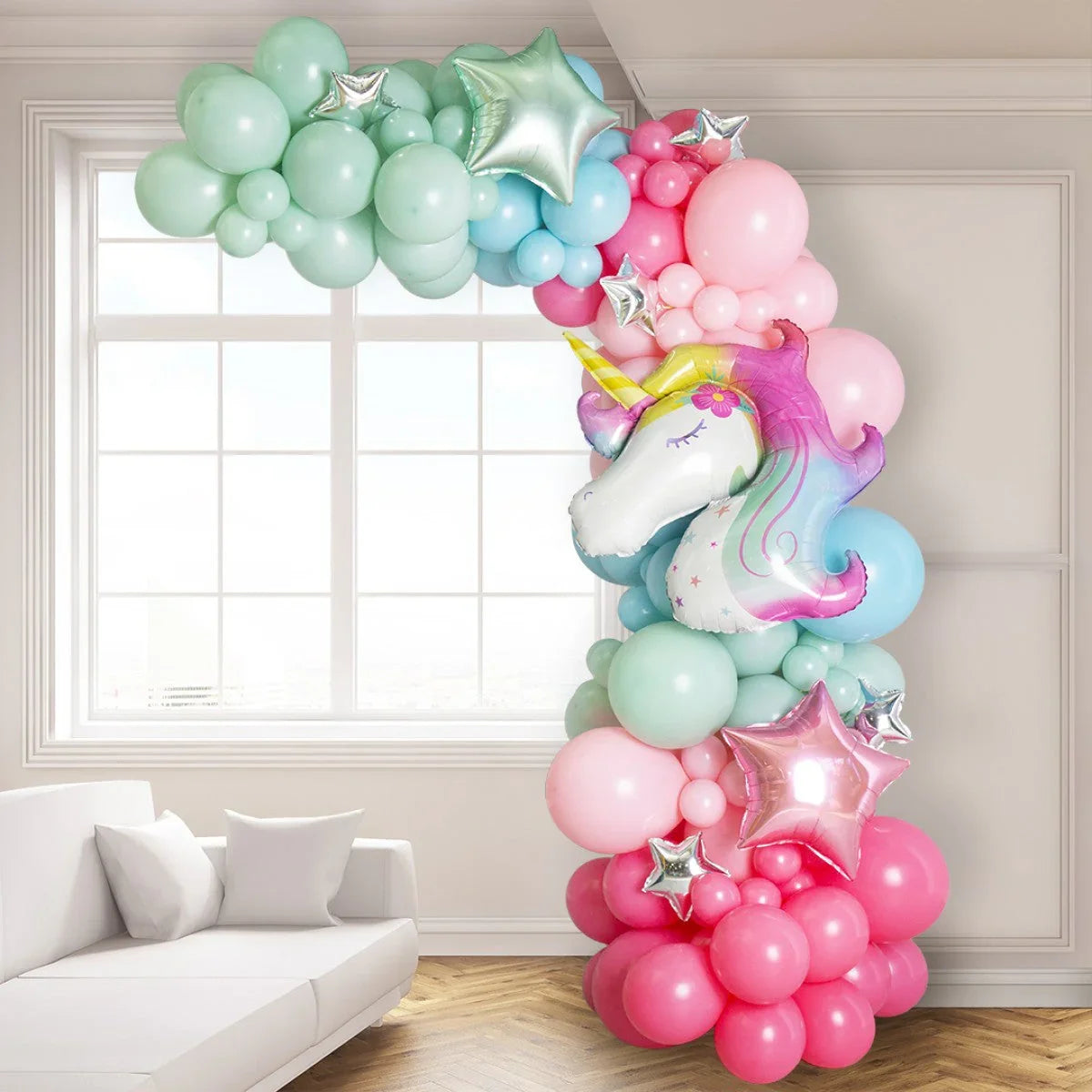 colorful pastel balloon arch with a large unicorn foil balloon and star-shaped balloons in a bright living room