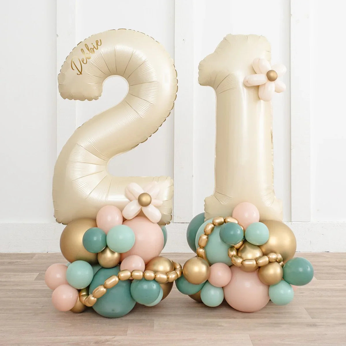 Personalized gold number 21 balloons with pastel pink, teal, and gold balloon decorations on wooden floor