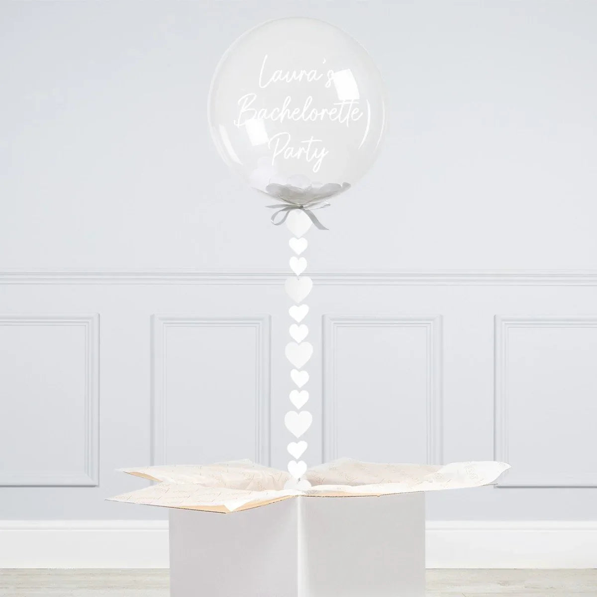 Clear personalized bubble balloon with white confetti and heart garland in white gift box
