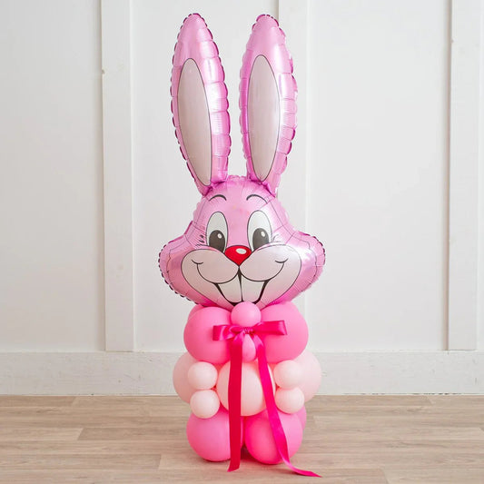 Pink Easter bunny balloon decoration with foil bunny face and tied pink ribbon on wooden floor