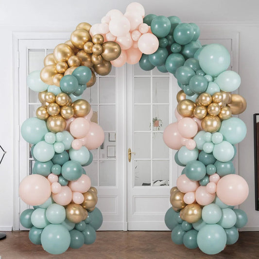 Elegant balloon arch in sage green, gold, and blush pink in a modern white room