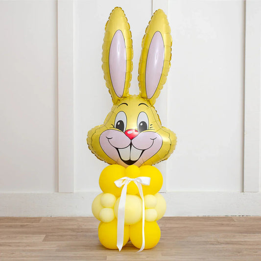 Yellow Easter bunny balloon sculpture with inflated face and body balloons tied with white ribbon