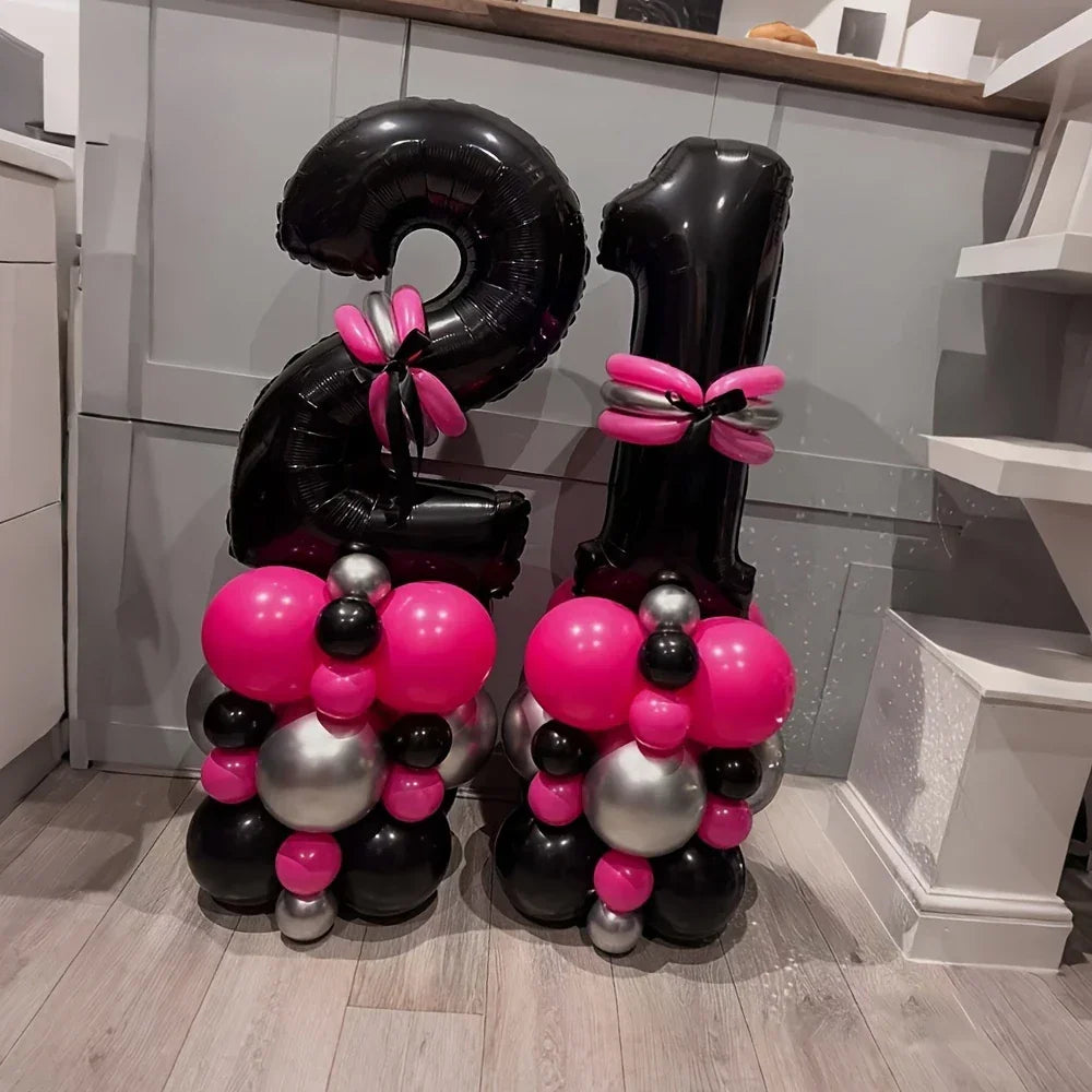 Black number 21 balloons with pink and silver balloon decorations on wooden floor in kitchen