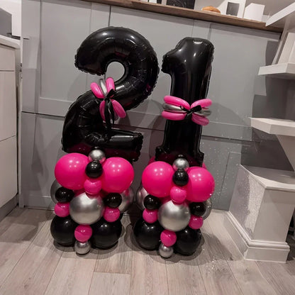Black number 21 balloons with pink and silver balloon decorations on wooden floor in kitchen
