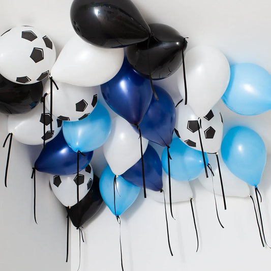 Helium balloons in black, white, blue, and soccer ball printed designs floating on a white ceiling
