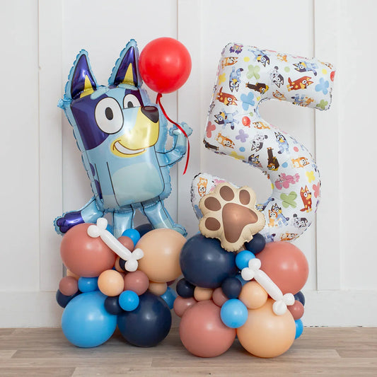 Bluey character balloon holding red balloon next to number 5 balloon with paw and bone accents on colorful balloon base