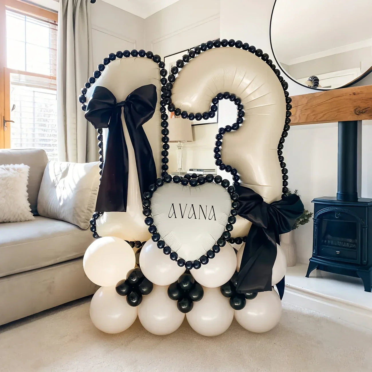 White number 13 balloon decoration with black bows and heart balloon reading Avana in a cozy living room
