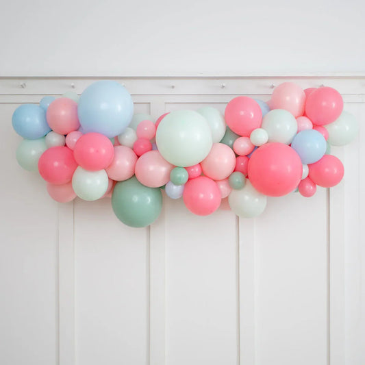 Colorful pastel balloon garland with pink, blue, green, and white balloons on white wall